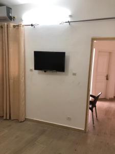 TV de pantalla plana en una pared blanca con silla en Chambre tout confort avec salle de bain intérieure privée - Clim & breakfast, en Saint-Louis