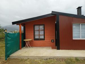 Uma casa vermelha com um banco à frente. em Casa para 4 personas em San Carlos de Bariloche