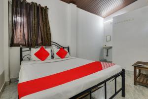 a bedroom with a large bed with red pillows at OYO Pratisha Guest House in Baga