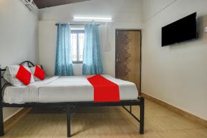 a bedroom with a bed with a television and a window at OYO Pratisha Guest House in Baga