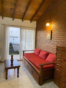 een woonkamer met een rode bank en een bakstenen muur bij LAS DACHAS 2 Villa Gesell in Villa Gesell