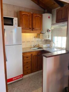 een keuken met een witte koelkast en houten kasten bij LAS DACHAS 2 Villa Gesell in Villa Gesell