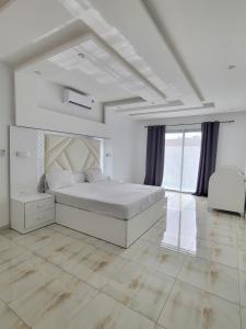 Un dormitorio blanco con una cama grande y una ventana grande. en Résidence Jordan, en Dakar