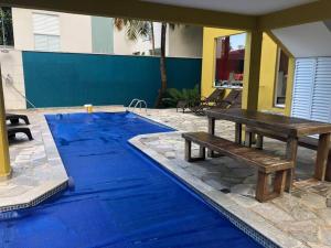 uma mesa de piquenique ao lado de uma piscina azul em Sobrado c/ PISCINA na Barra do Una (Litoral Norte) em São Sebastião