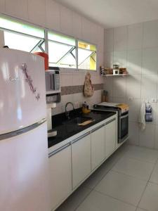 uma cozinha com um frigorífico branco e um lavatório em Sobrado c/ PISCINA na Barra do Una (Litoral Norte) em São Sebastião