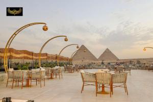 um grupo de mesas e cadeiras com pirâmides ao fundo em Comfort Inn Giza no Cairo