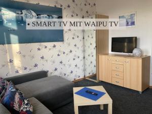 ein Wohnzimmer mit einem Sofa und einem TV in der Unterkunft Krabbe Apartment 6, zentral gelegen, ideal für Paare, bis zu 2 Hunden kostenfrei willkommen, gute Zuganbindung, am Elbe-Weser-Radweg, Geschäfte und Restaurant 2 Minuten entfernt in Wremen