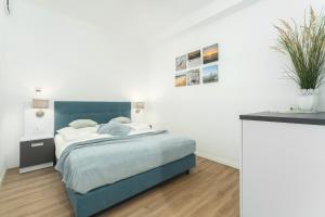 a bedroom with a bed with a blue headboard at Apartament Niebieski c4 in Pobierowo