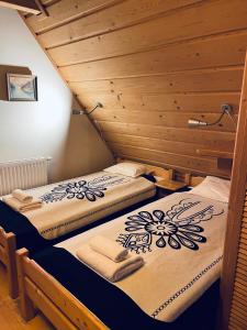 two beds in a room with wooden walls at Dom Z Witrażami in Bukowina Tatrzańska