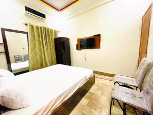 um quarto com uma cama, uma televisão e uma cadeira em Airport Hotel Bed & Rest em Karachi