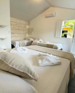 Habitación con 4 camas y toallas. en Pousada Amora Caraiva, en Caraíva