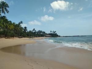 einen Sandstrand mit Palmen und dem Meer in der Unterkunft Sandhara Home Stay in Tangalle