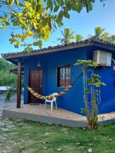 a blue house with a hammock in front of it at Chalés Rio Bonito in Imbassai