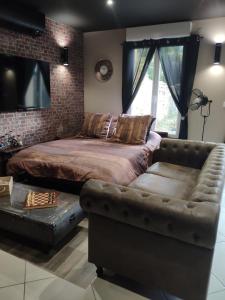a bedroom with a bed and a leather couch at LE MANHATTAN Authentique maison climatisée 78 m2 in Brasles