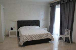 a bedroom with a bed and a chair and a window at Hotel Presidente in Porto Cesareo