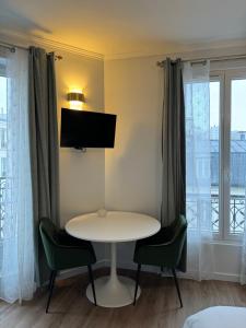 Zimmer mit einem Tisch und Stühlen sowie einem TV in der Unterkunft Studio de charme parisien in Levallois-Perret