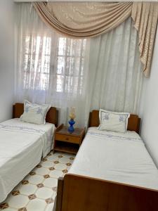 two beds in a room with a window at Slama in Nabeul