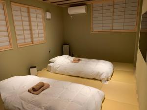 two beds in a room with windows and white sheets at Ito Ryokan in Tokyo