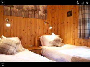 two beds in a room with wood paneled walls at The Crannog on Loch Tay in Morenish