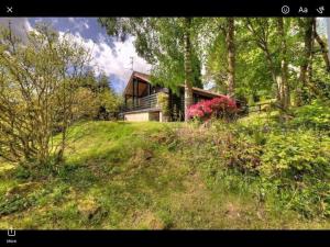 a house sitting on top of a grassy hill at The Crannog on Loch Tay in Morenish