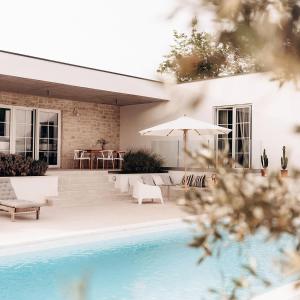 einem Pool mit Stühlen und einem Sonnenschirm neben einem Haus in der Unterkunft Villa Sunrise in Labin