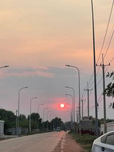 einen Sonnenuntergang auf einer Straße mit Straßenbeleuchtung in der Unterkunft Dontrei Villa Angkor in Siem Reap