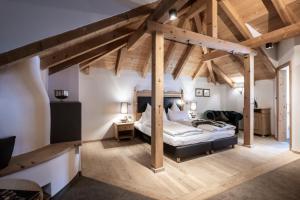 a master bedroom with a large bed and wooden beams at Hotel Acadia - Adults Mountain Home in Selva di Val Gardena