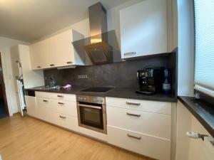 シュルンスにあるAlpenwohnungen Ruprecht Montafonの白いキャビネットとコンロ付きオーブンを備えたキッチン