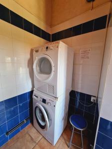 a washing machine in a bathroom with a stool at Albergue Laganares 