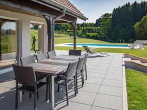 a wooden table and chairs on a patio at Villa Le Chant des Sapins - Tennis, Pool, Golf in Le Saulcy