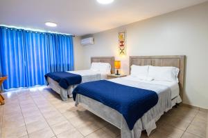 Cette chambre comprend 2 lits et des rideaux bleus. dans l'établissement Golden Dreams Studio 306 B, à Isabela