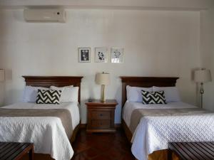a bedroom with two beds and a night stand with two lamps at Hotel El Farol in Parras de la Fuente