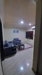 ein Wohnzimmer mit einem blauen Sofa und einem TV in der Unterkunft شقق مساكن السمو المخدومة in Ad-Dawādimi