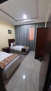 una camera d'albergo con due letti e una finestra di شقق مساكن السمو المخدومة ad Ad Dawādimī