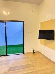 ein leeres Zimmer mit einem großen Fenster und einem Flachbild-TV in der Unterkunft Villa Mamath 