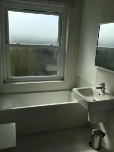 a bathroom with a tub and a sink and a window at Two bedroom flat, North Oxford in Oxford