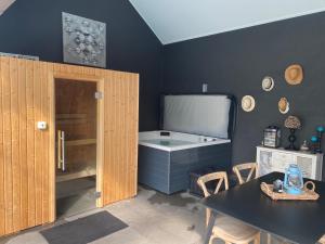 een badkamer met een bad en een tafel met stoelen bij Le petit studio de l'espace bien être in Libin