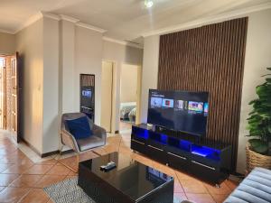 ein Wohnzimmer mit einem großen TV und einem Stuhl in der Unterkunft The lion Sands Apartment in Pretoria