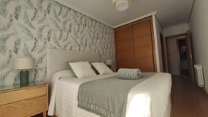 a bedroom with a bed with a green and white wallpaper at O pisiño de Vista Alegre in Vilagarcia de Arousa