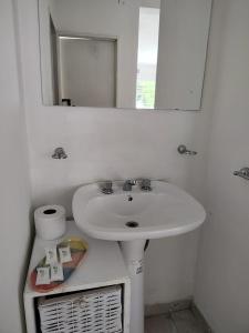 Baño blanco con lavabo y espejo en Departamento W R T 1 en Villa Carlos Paz