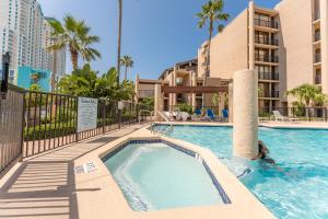 a swimming pool at a resort with palm trees and buildings at 219 Sea Vista - Beach Front in South Padre Island