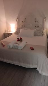 Una cama blanca con dos toallas y flores. en Apts con encanto y patio en monfrague, en Torrejón el Rubio