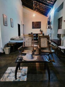 une chambre avec des chaises, une table et un lit dans l'établissement The Bungalow Bogmalo An 1880 Indo Portuguese Heritage Beach Villa South Goa, à Bogmalo Beach