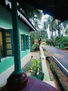 a green building with a pole next to a street at The Bungalow Bogmalo An 1880 Indo Portuguese Heritage Beach Villa South Goa in Bogmolo