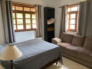 a bedroom with a couch and a bed and windows at Lumiar centro com Wi-FI aconchegante apartamento com 2 quartos mobiliado com ventiladores in Lumiar +17 photos