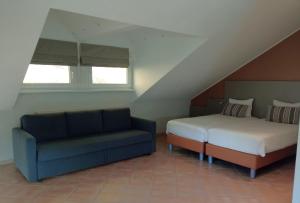 a bedroom with a bed and a couch in a attic at Appart-Hotel Gwendy in Bour