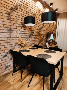 comedor con pared de ladrillo, mesa y sillas en Asti Apartamenty Centrum Stargard, en Stargard
