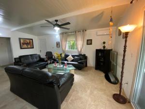uma sala de estar com mobiliário de couro preto e uma ventoinha de tecto em Aeolus Guest House em José Pobre