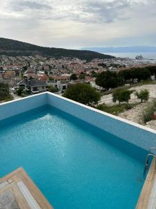 a blue swimming pool with a view of a city at Nova Butik Hotel Çeşme in Cesme