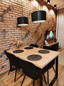 una mesa de madera en una habitación con una pared de ladrillo en Asti Apartamenty Centrum Stargard, en Stargard